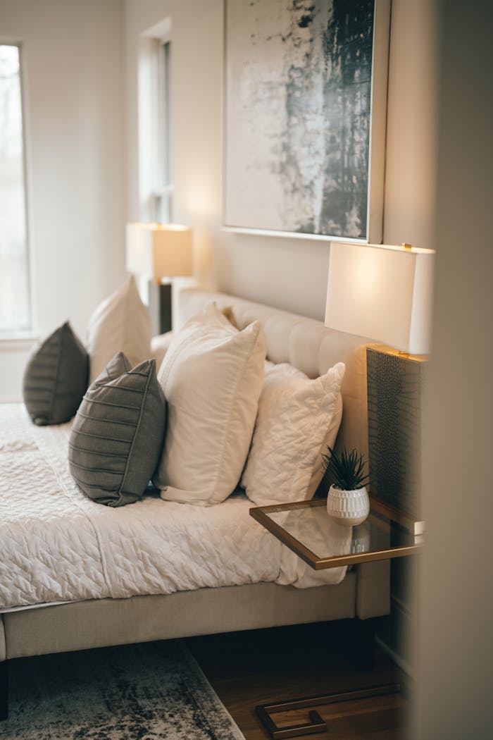 A warm and inviting bedroom featuring stylish bedding, soft lighting, and contemporary art.