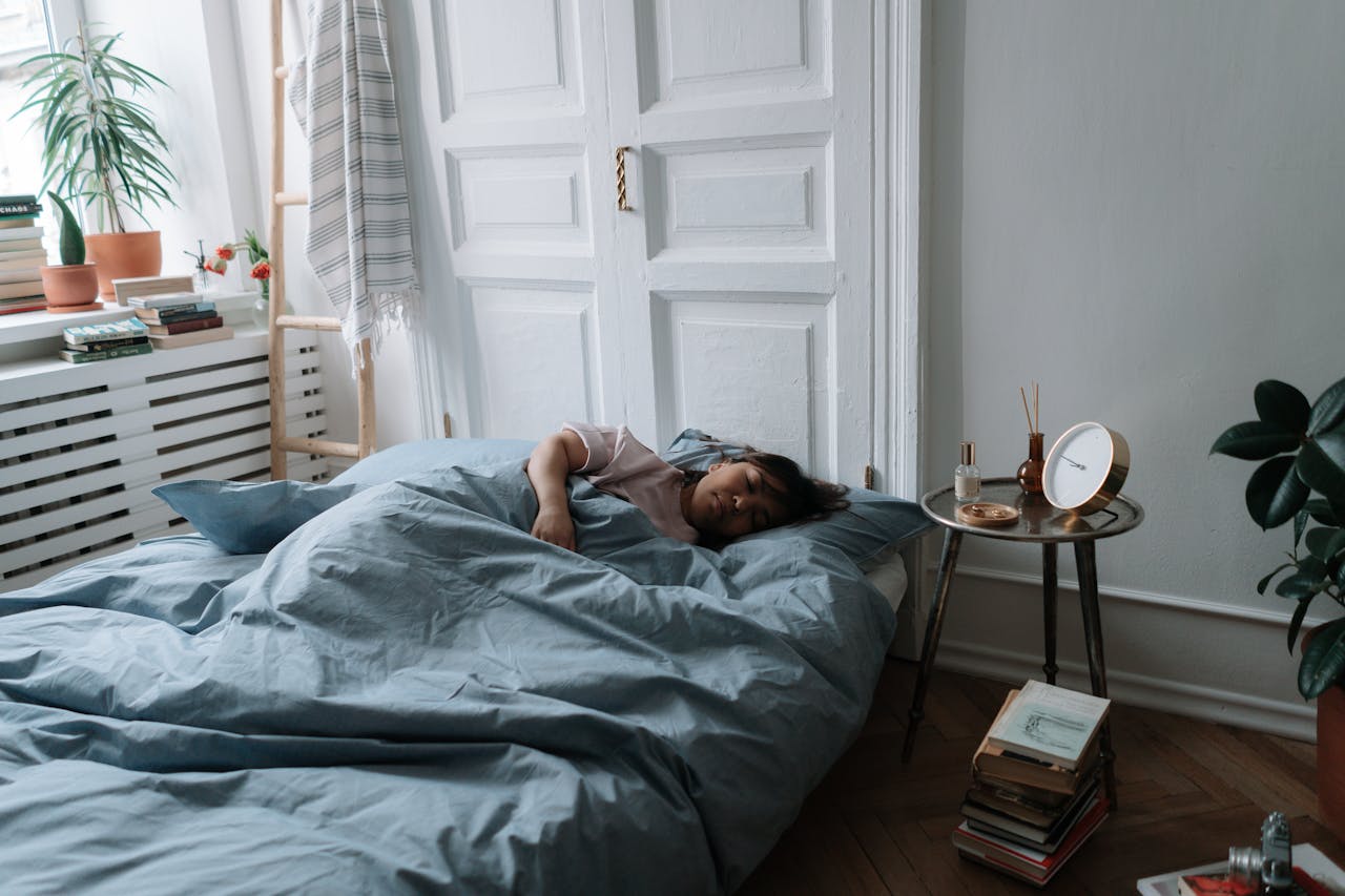 Woman sleeping in a cozy bedroom with soft morning light and plants.
